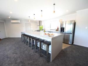 a kitchen with a long counter with stools and a refrigerator at Mata-au Lodge in Beaumont