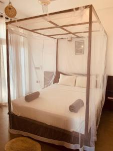 a bedroom with a canopy bed with white sheets and pillows at Thaproo Bay Hiriketiya in Dickwella
