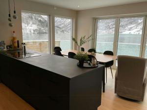 a kitchen with a table and chairs and windows at Newly Built Cabin With Sauna By Oldevatnet in Olden