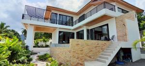 a house with a balcony on the side of it at Rancho Relaxo Pool Villa in Nathon Bay