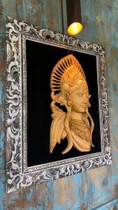 a gold statue in a picture frame on a wall at Pondok Satu Hati Sidemen in Sidemen