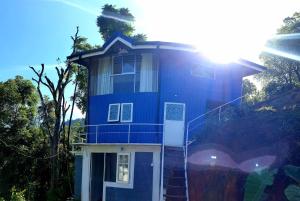 a blue house with the sun shining on it at Kithul Cottage 2 in Watagoda +9 photos