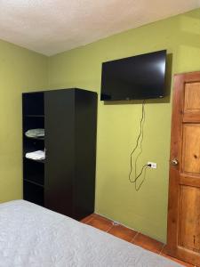 a bedroom with a television on a green wall at Casa fide cómoda in Panajachel