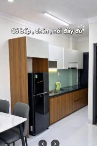 a kitchen with a black refrigerator and white cabinets at The Tiny Cineroom & Homestay in Buon Ma Thuot