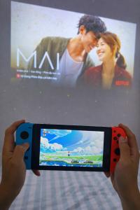 a person holding a video game controller in front of a movie sign at The Tiny Cineroom & Homestay in Buon Ma Thuot