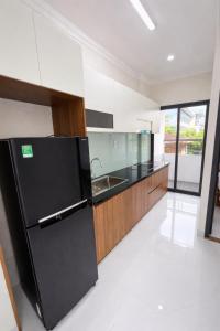 a kitchen with a black refrigerator and a sink at The Tiny Cineroom & Homestay in Buon Ma Thuot