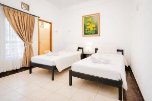 two beds in a room with a window at Tripletree Sinergi Hotel Tretes in Pasuruan +81 photos