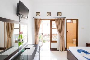 a room with a bed and a television on a wall at Tripletree Sinergi Hotel Tretes in Pasuruan