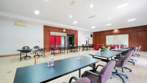a conference room with tables and chairs and a screen at Tripletree Sinergi Hotel Tretes in Pasuruan