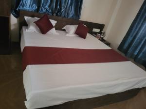 a bedroom with a large bed with red and white pillows at Hotel Kunj Palace in Habibnagar
