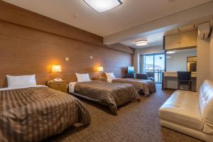 a hotel room with two beds and a couch at Uomisaki Hotel in Atami