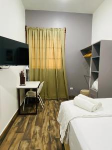 a room with two beds and a desk and a television at 8 habitaciones para 16 personas in Flores