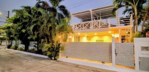 a house with a fence and palm trees in front of it at Leelawadee Pool Villa BBQ&Pool party in Bang Sare