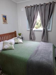 a bedroom with a bed with a green blanket and a window at Espaço Van Gogh Poços de Caldas in Poços de Caldas