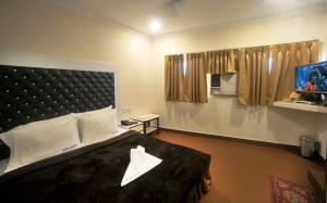 a bedroom with a large bed and a tv at Hotel Raunak in Kolkata