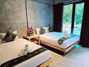 two beds in a room with a window at คีรีเขาสกริเวอร์ Keereekhaosokriver in Khao Sok National Park