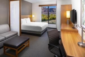 a hotel room with a bed and a couch and a tv at Hyatt Place Moab in Moab