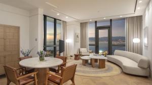 a living room with a couch and tables and windows at Grand Hyatt Izmir IstinyePark in İzmir