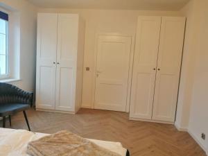 a bedroom with white cabinets and a bed and a chair at Gemütlich & stilvoll in Tuchola +4 photos