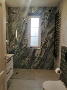 a bathroom with a marble wall with a window at Gemütlich & stilvoll in Tuchola