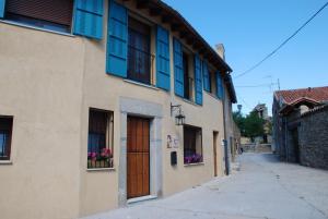 Un callejón en un pueblo con ventanas azules y una puerta. en El Capricho de Ana, en Neila de San Miguel