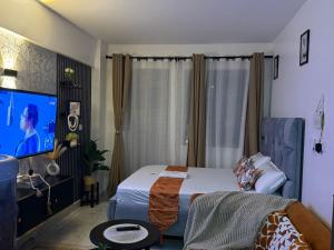 a bedroom with a bed and a flat screen tv at Membley star heights -Naivera in Ruiru