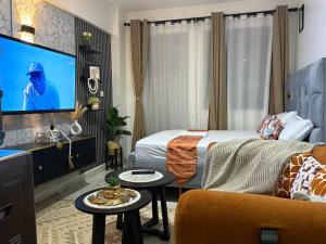 a hotel room with a bed and a flat screen tv at Membley star heights -Naivera in Ruiru
