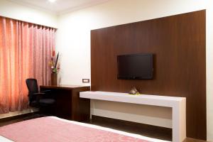 a hotel room with a flat screen tv on a wall at Ramyas Hotel in Tiruchchirāppalli