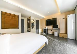 a large bedroom with a white bed and a tv at Brown Dot Yeongildae Beach in Pohang in Pohang