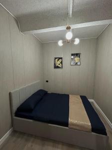 a bedroom with a bed with blue sheets and a ceiling at Villa De Ray in Almaty