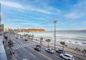 a road with cars parked on it next to the beach at Brown Dot Yeongildae Beach in Pohang in Pohang
