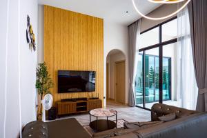 a living room with a couch and a tv at นารา พลูวิลล่า in Cha Am