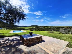 a stone bench sitting next to a swimming pool at SoetHoek Farm Retreat in Alexandria
