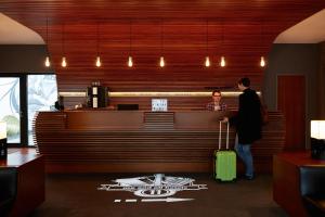 a man and a woman standing at a bar with a suitcase at Me and All Hotel Dusseldorf, by Hyatt in Düsseldorf