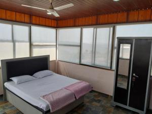 a bedroom with a bed in a room with windows at Sattva Gruha in Māngaon