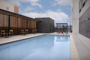 a swimming pool with chairs and tables on a building at Home2 Suites By Hilton Taylor in Taylor