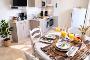 a kitchen with a table with food and glasses of orange juice at Residence Clos des Aigrettes -Appartements a 30m du Port de La Cotiniere , Ile d Oleron -commerces et plages a pied in La Cotinière