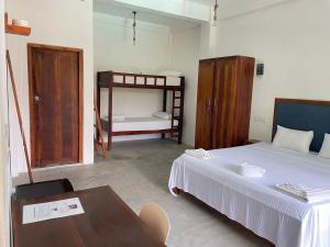 a bedroom with a bed and a table and a bunk bed at Surf Gangs Arugambay in Arugam Bay