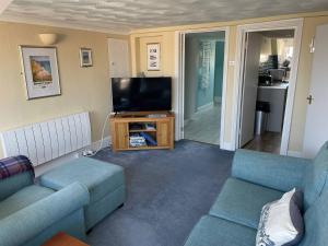 a living room with two couches and a flat screen tv at Monarch in Weymouth