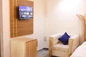 a room with a chair and a tv on a wall at Oasis hotel and suites in Lagos