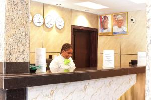 a woman sitting at a counter in a room with clocks at Oasis hotel and suites in Lagos