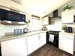 a kitchen with white cabinets and a black stove top oven at Dunlin Retreat in Flamborough