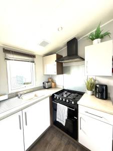 a kitchen with white cabinets and a black stove top oven at Dunlin Retreat in Flamborough