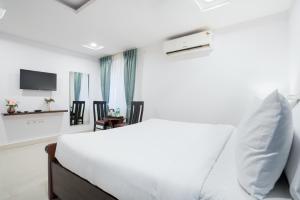 a white bedroom with a bed and a tv at RCC Hotels Parkview Inn Miyapur in Lingampalli