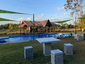 a picnic table in the grass next to a pool at Isaan Country Retreat in Mukdahan