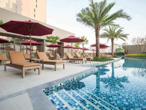 a pool with chairs and umbrellas next to a hotel at Mercure Pattaya Ocean Resort in Pattaya