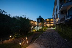a building with a stone pathway next to a building at night at Tethys Himalaya Resort in Solan