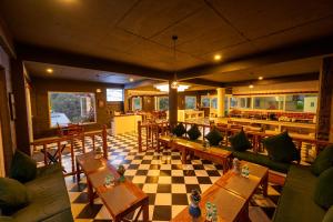a restaurant with couches and tables and a checkered floor at Tethys Himalaya Resort in Solan