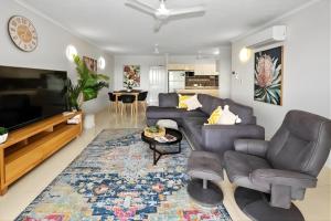 a living room with a couch and a tv at Sunset Stunner Marina Views in Larrakeyah