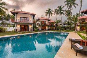 a villa with a swimming pool in front of a house at Arinna Beach Resort in Tangalle